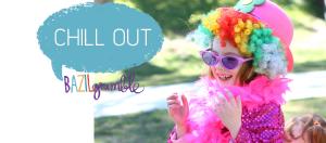 A child dressed in a multicoloured wig, sunnies and bright costume. The chillout bazil grumble logo is over the top.